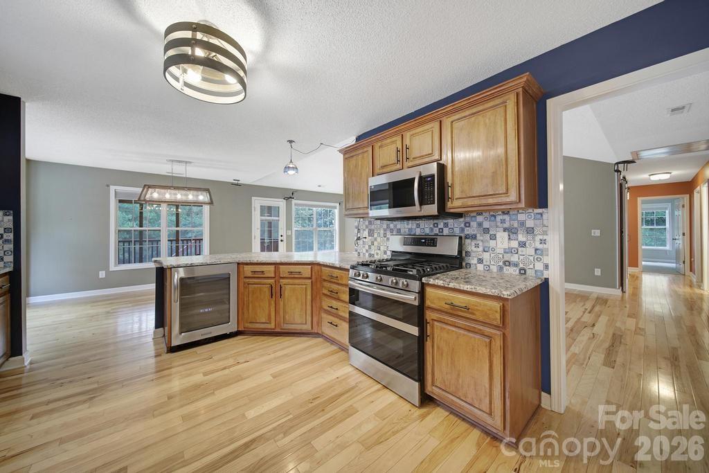 4394 Mountain Creek Road Iron Station, NC 28080 - Photo 11 of 45 a kitchen with stainless steel appliances granite countertop a stove top oven a sink dishwasher a dining table and chairs with wooden floor