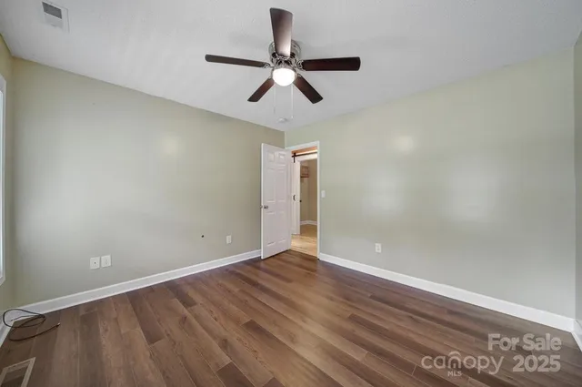 an empty room with wooden floor and ceiling fan