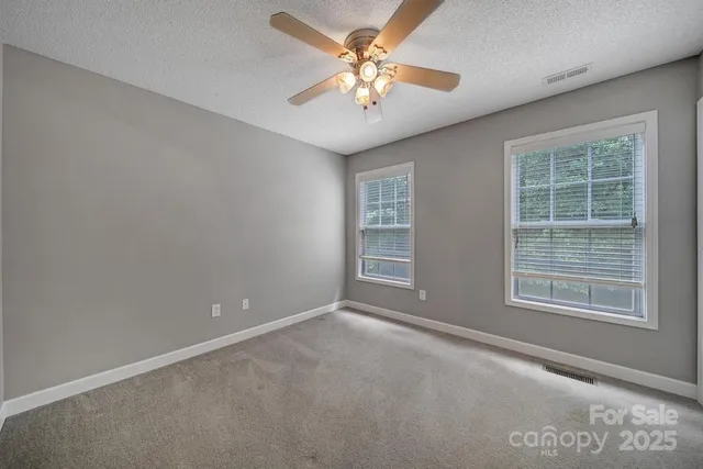 an empty room with windows and fan