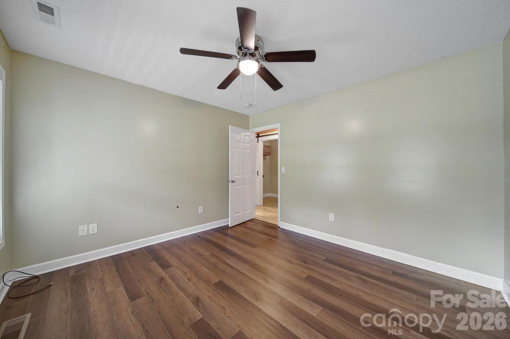 4394 Mountain Creek Road Iron Station, NC 28080 - Photo 15 of 45 an empty room with wooden floor and ceiling fan