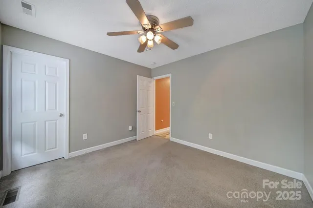 an empty room with a chandelier fan and windows