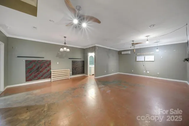 a view of an empty room with a chandelier fan and a window