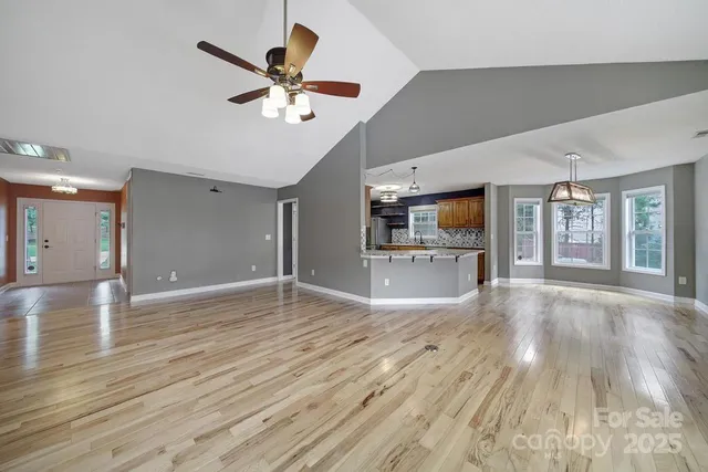 a view of an empty room with window and wooden floor