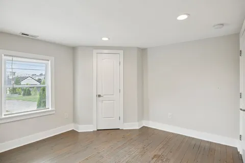 a bathroom with a toilet a sink a mirror and a window