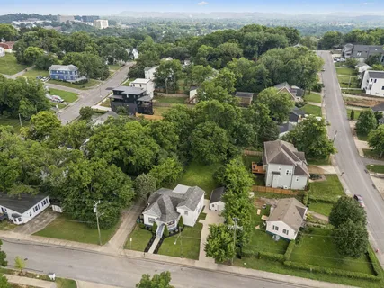 an aerial view of residential houses with outdoor space and trees