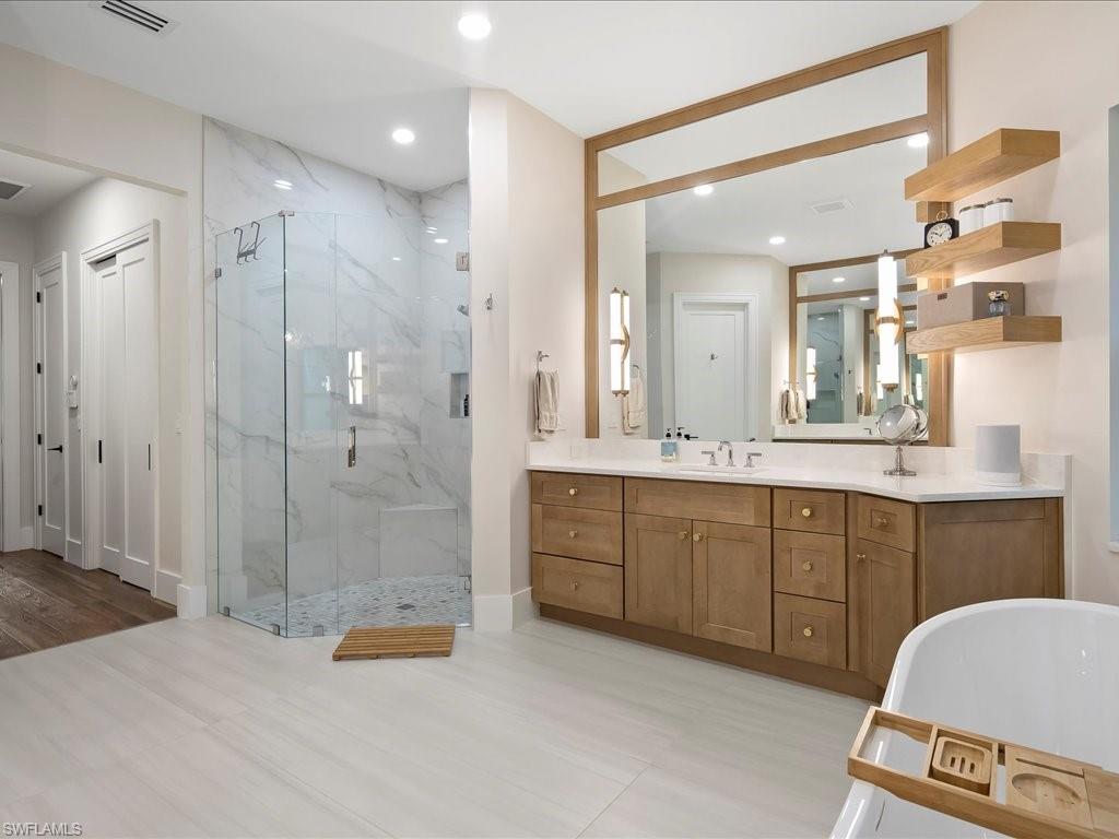 2590 2nd Street Northwest Naples, FL 34120 - Photo 24 of 49 Standout features of the bathroom remodel are the oversized vanities with quartz countertops and floating shelves accented by newly installed pendant lights. The natural stone shower is oversized and boasts multiple shower heads.