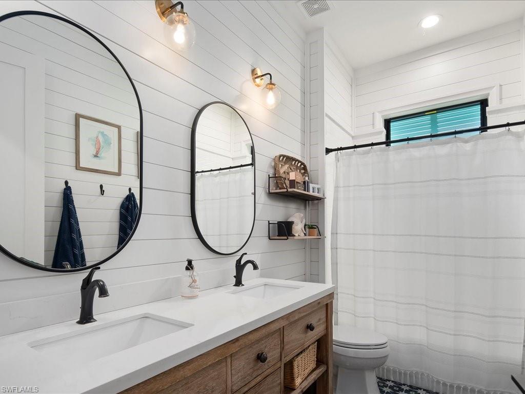 2590 2nd Street Northwest Naples, FL 34120 - Photo 30 of 49 The third full bathroom boasts a double vanity, custom tile features, and shiplap walls, complementing the nautical theme.