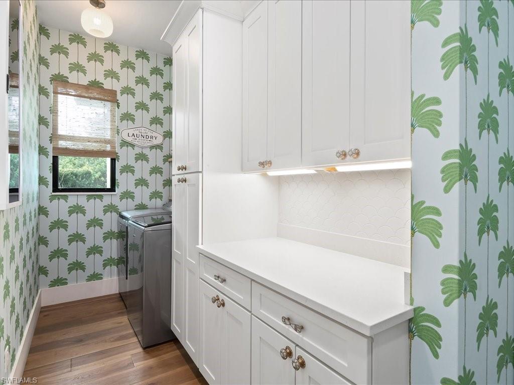 2590 2nd Street Northwest Naples, FL 34120 - Photo 36 of 49 Who wouldn't enjoy laundry in this room? You'll love the fun palm tree wallpaper in addition to the new cabinets, whimsical light fixture, and tile backsplash.