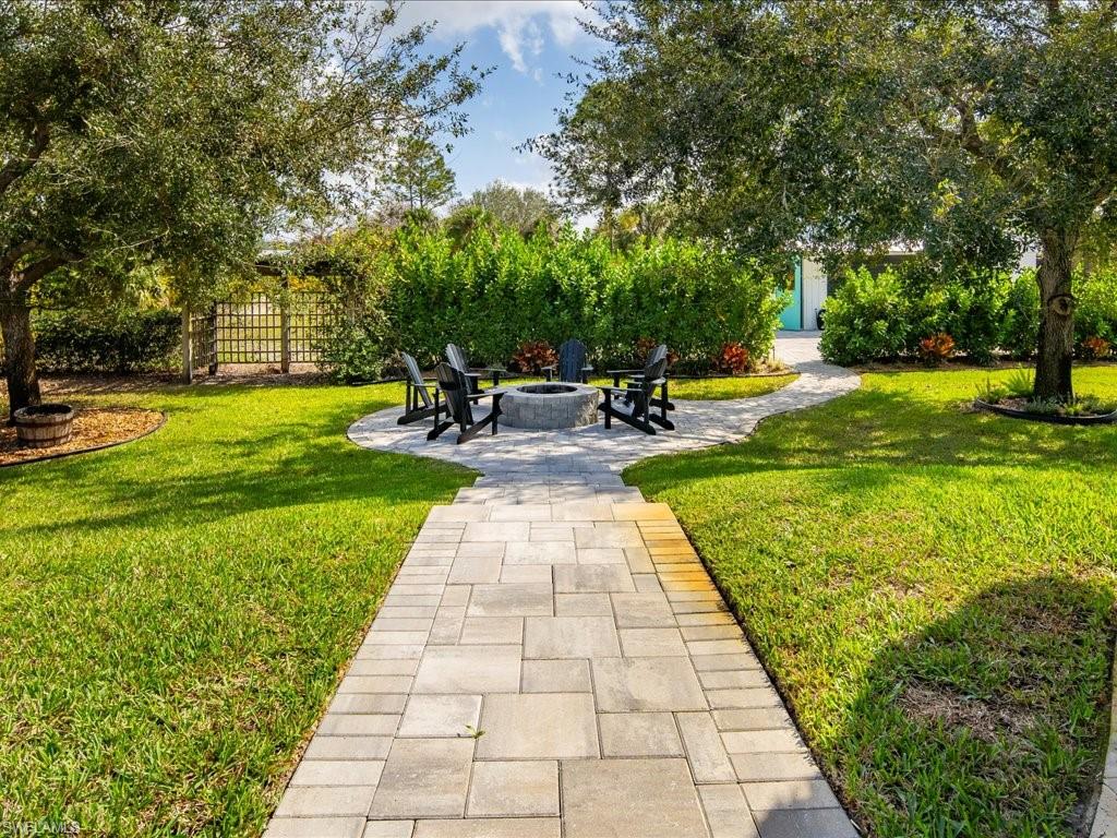 2590 2nd Street Northwest Naples, FL 34120 - Photo 47 of 49 A few steps down from the pool and chickee hut is the built-in firepit with paver surround.
