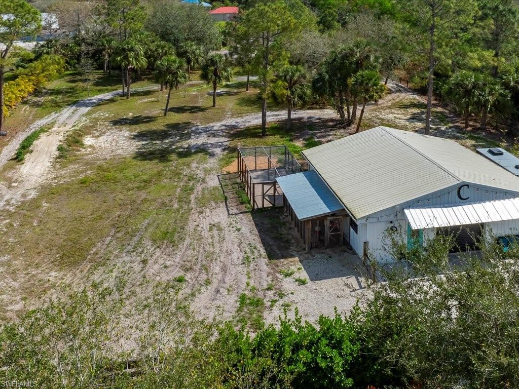 2590 2nd Street Northwest Naples, FL 34120 - Photo 48 of 49 The back of the property has endless potential but is currently being happily used as a motorcross track! You can also see a bit of the extensive custom chicken coop and run built on to the side of the barn. You'll never have to worry about the price of eggs again!