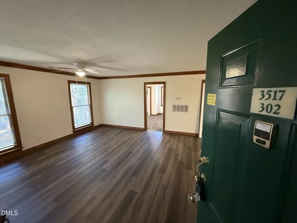 a view of an empty room with wooden floor and a window