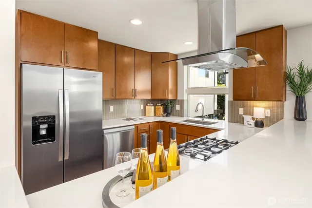 a kitchen with stainless steel appliances granite countertop a refrigerator a stove and a sink