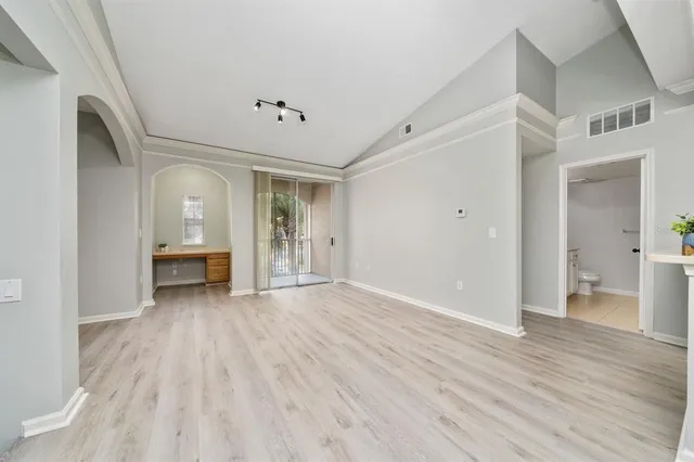 a view of an empty room with wooden floor and a bathroom