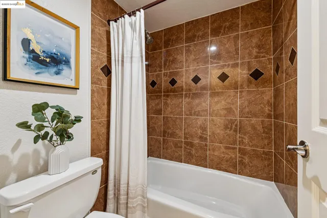 a bathroom with a granite countertop sink a toilet a mirror a bathtub and shower