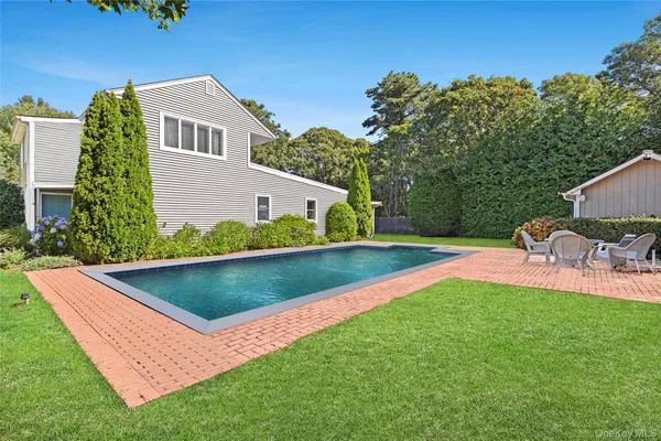 a view of a backyard with chairs under an umbrella
