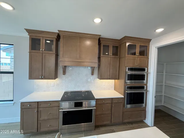 a living room with stainless steel appliances wooden floors and kitchen view