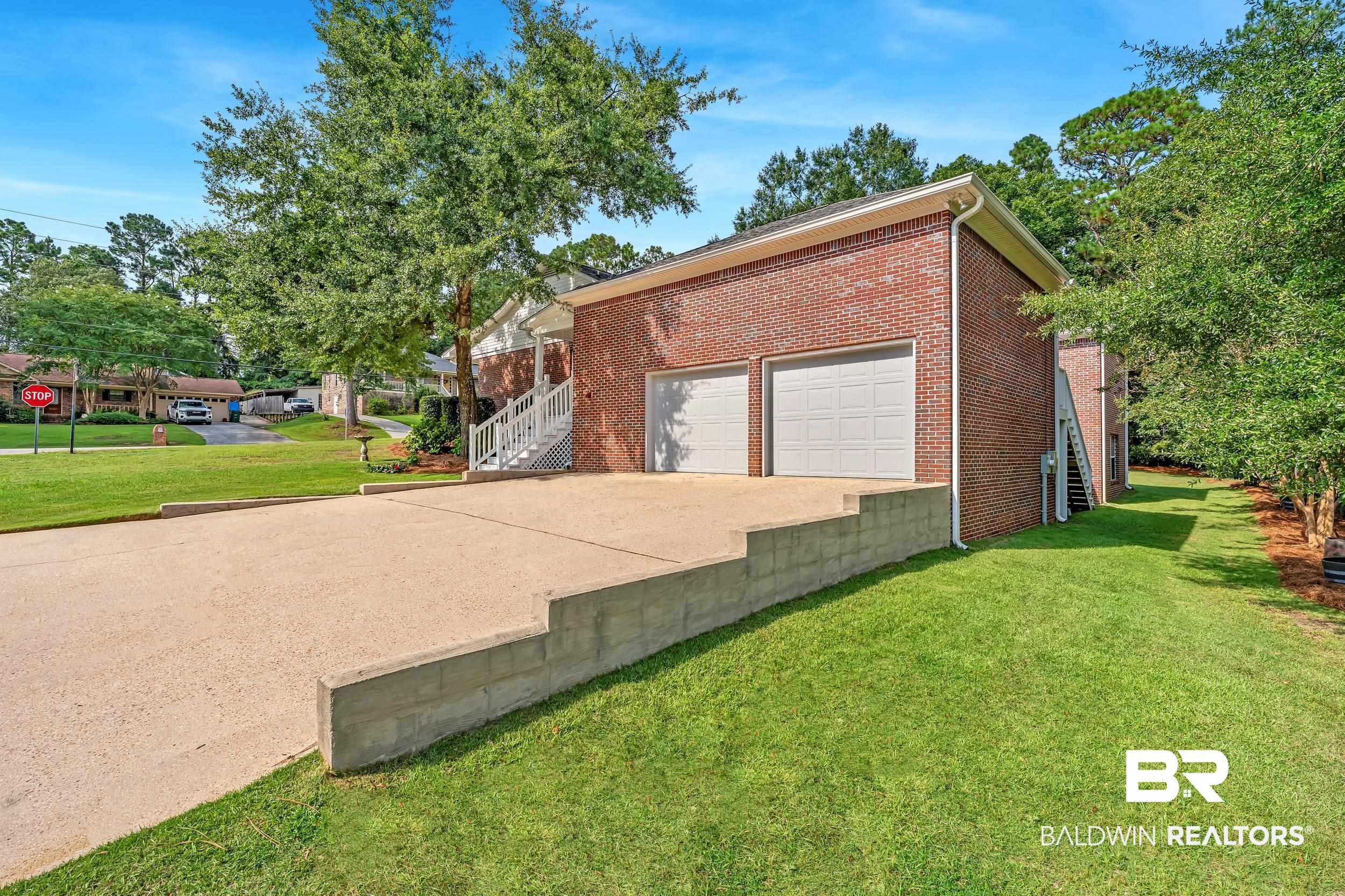 2 Navy Lane Daphne, AL 36527 - Photo 4 of 28 View of property exterior with a yard, brick siding, driveway, and stairs