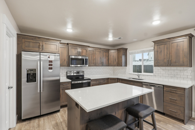 2011 Wren Circle Logan, UT 84339 - Photo 10 of 20 Kitchen featuring appliances with stainless steel finishes, a breakfast bar, a center island, and light wood-type flooring