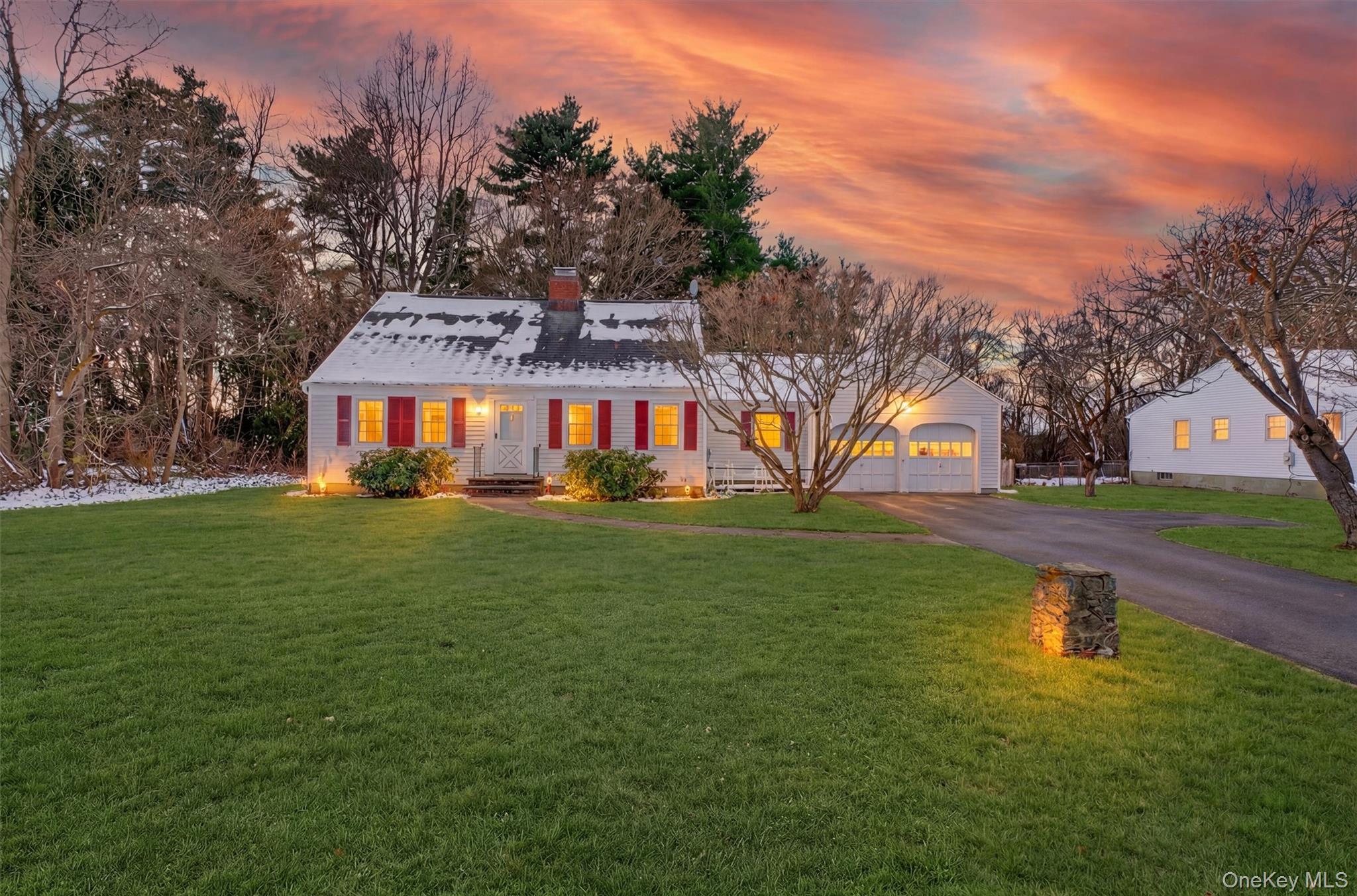 View of front facade featuring asphalt driveway, a lawn, a chimney, and a garage