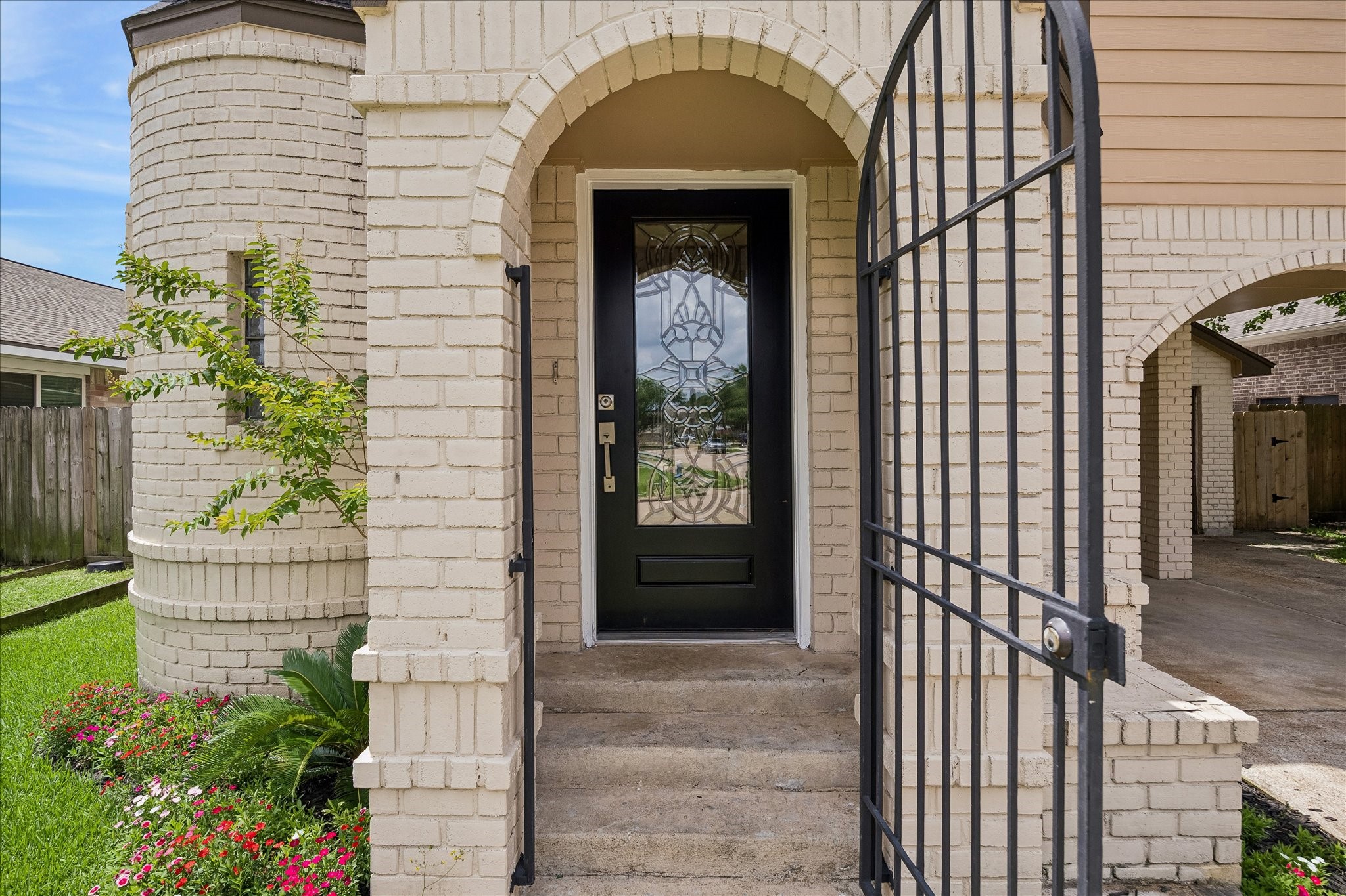 10411 Goodrum Road Houston, TX 77041 - Photo 3 of 25 Private gated courtyard entry with wrought-iron gate, arched brick architecture, and a stunning decorative glass front door. A unique and elegant welcome that enhances the home’s storybook charm and curb appeal.