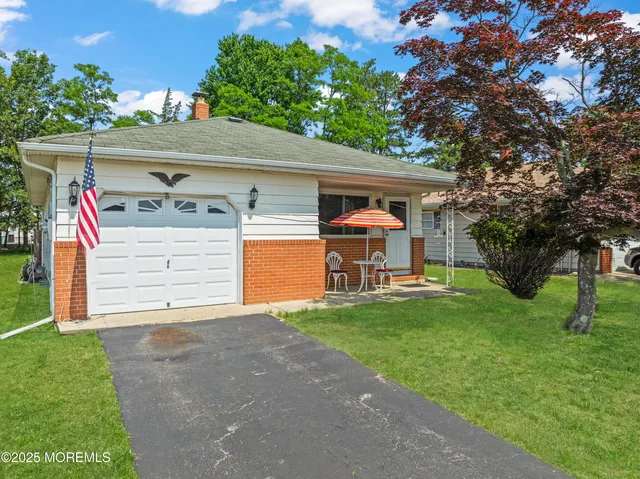 a view of a house with a yard and a large tree