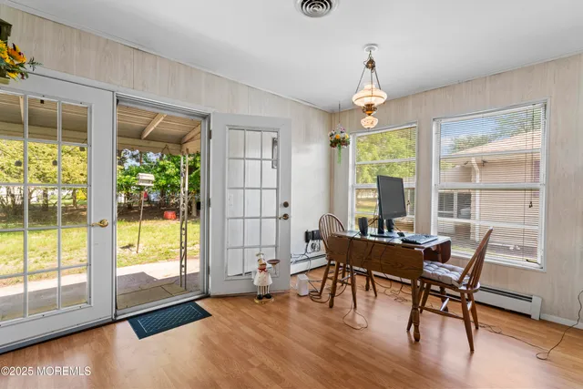 a dining room with wooden floor a chandelier a glass table and chairs