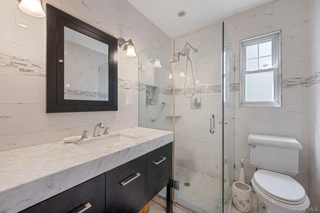 a bathroom with a toilet a sink a glass door a shower a mirror and vanity