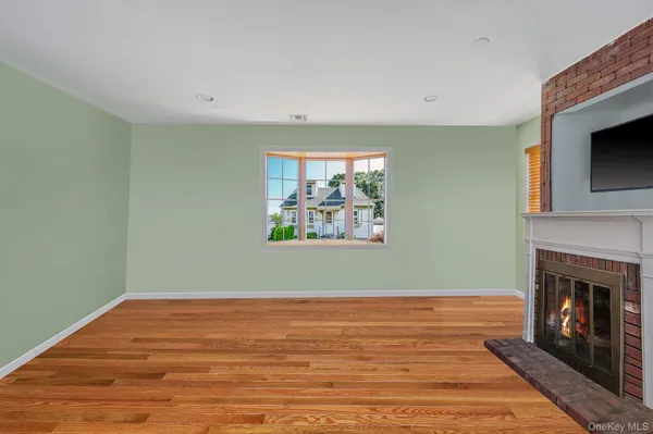 a view of empty room with wooden floor and fireplace