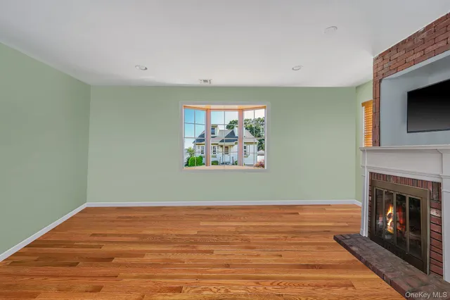 a view of empty room with wooden floor and fireplace