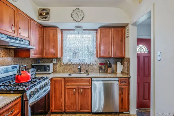 a kitchen with stainless steel appliances granite countertop a sink dishwasher cabinets and couches with wooden floor