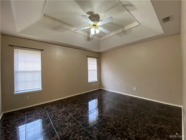 en empty room with windows and ceiling fan