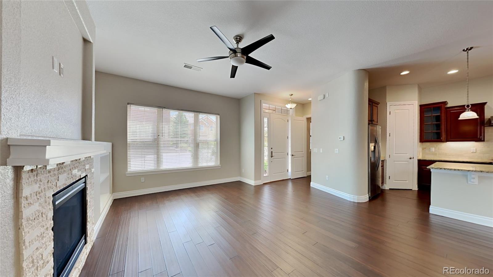 9237 Mornington Way Lone Tree, CO 80124 - Photo 5 of 24 a view of a livingroom with a ceiling fan a fireplace and wooden floor