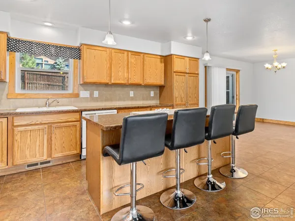 a kitchen with stainless steel appliances granite countertop a stove top oven a sink a dining table and chairs with wooden floor