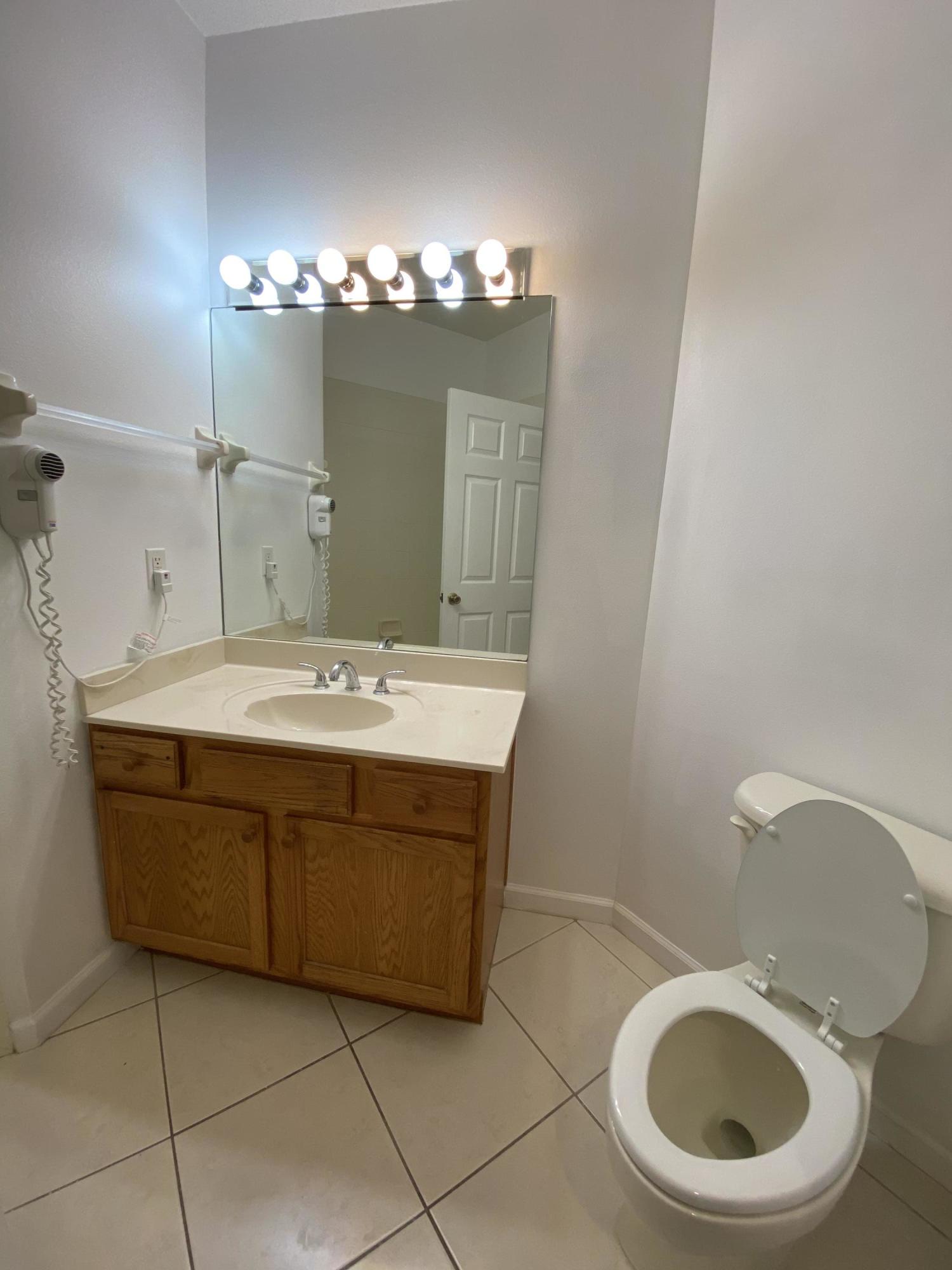 8377 Mulligan Circle, Unit SIDE B Port St. Lucie, FL 34986 - Photo 13 of 17 a bathroom with a sink a toilet and a mirror