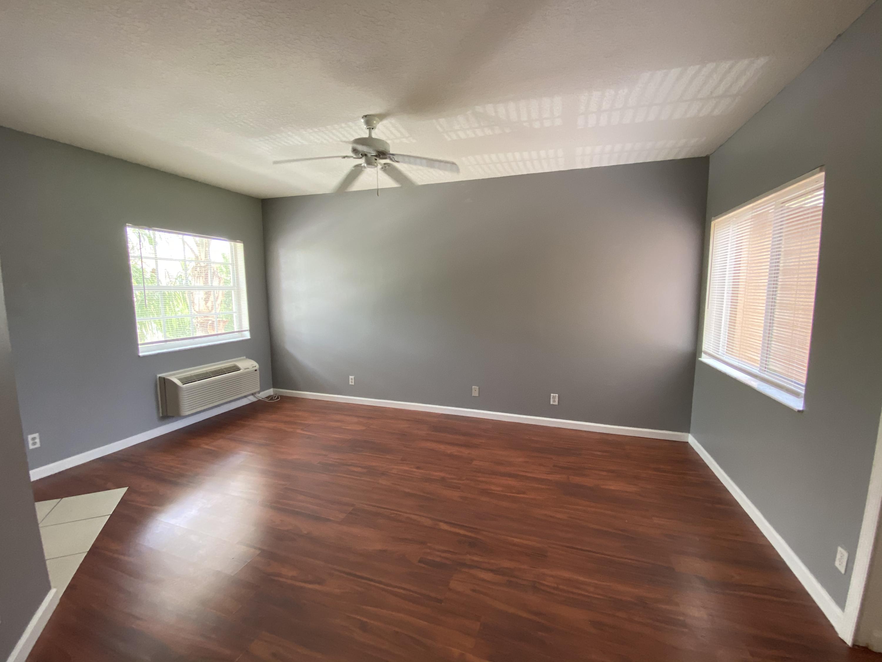8377 Mulligan Circle, Unit SIDE B Port St. Lucie, FL 34986 - Photo 15 of 17 an empty room with wooden floor fan and windows