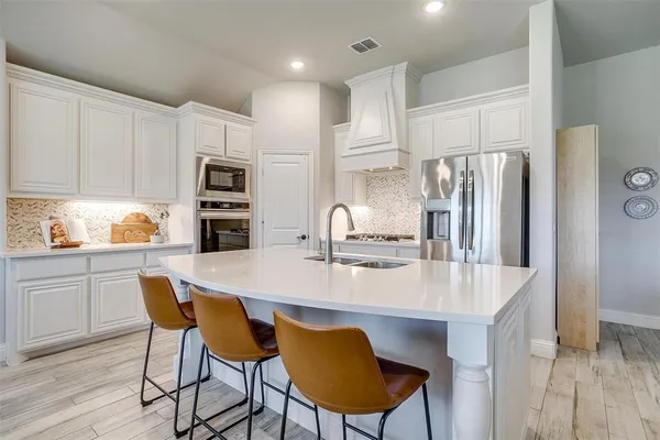 a kitchen with kitchen island a refrigerator stove and white cabinets