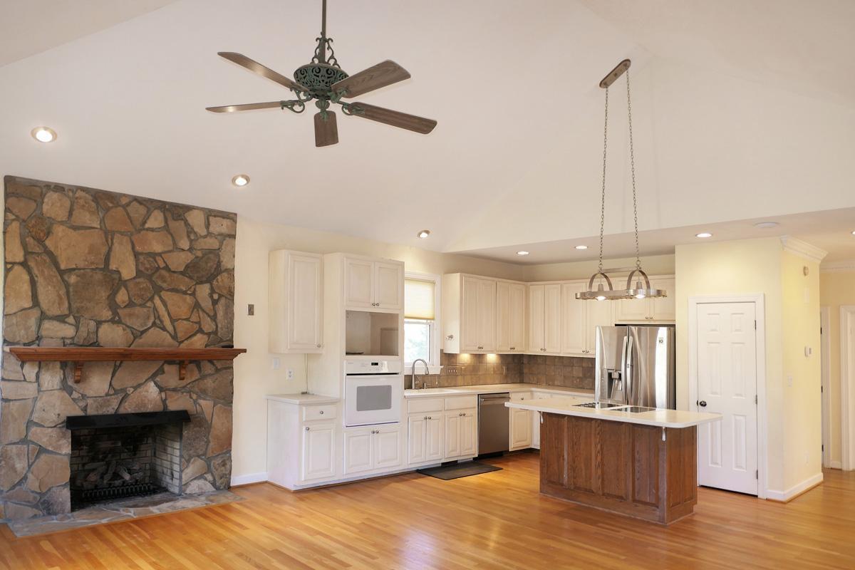 5330 Foxlair Road Chapel Hill, NC 27516 - Photo 17 of 43 a kitchen with stainless steel appliances kitchen island granite countertop a refrigerator a stove a sink and a fireplace with wooden floor