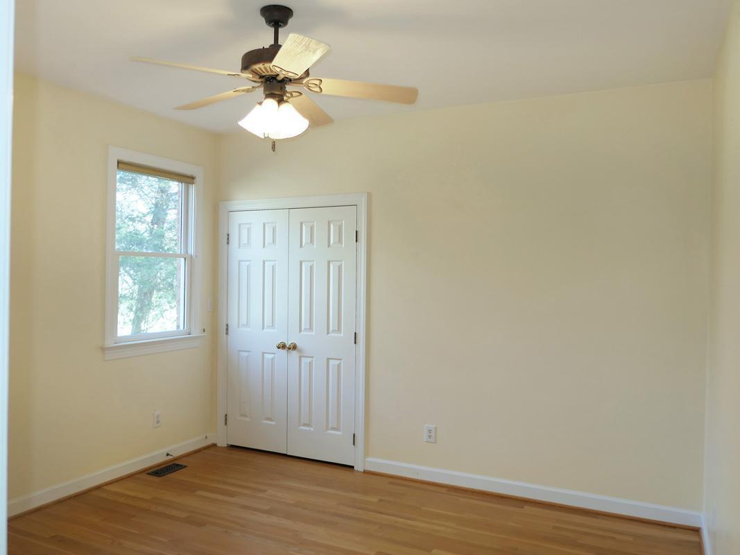 5330 Foxlair Road Chapel Hill, NC 27516 - Photo 21 of 43 an empty room with wooden floor chandelier fan and windows