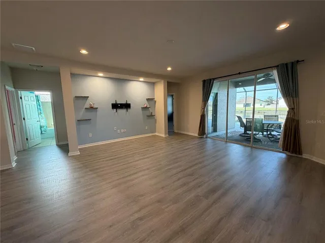 a view of a big room with wooden floor and a kitchen