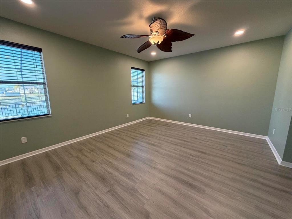 11342 77th Street East Parrish, FL 34219 - Photo 15 of 31 an empty room with wooden floor chandelier fan and windows