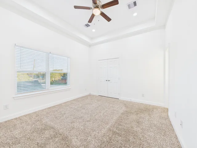 an empty room with windows and fan