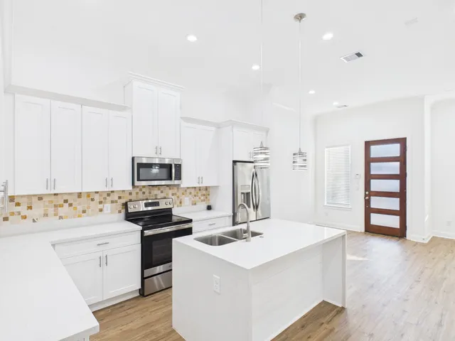 a kitchen with a sink a stove a refrigerator and white cabinets