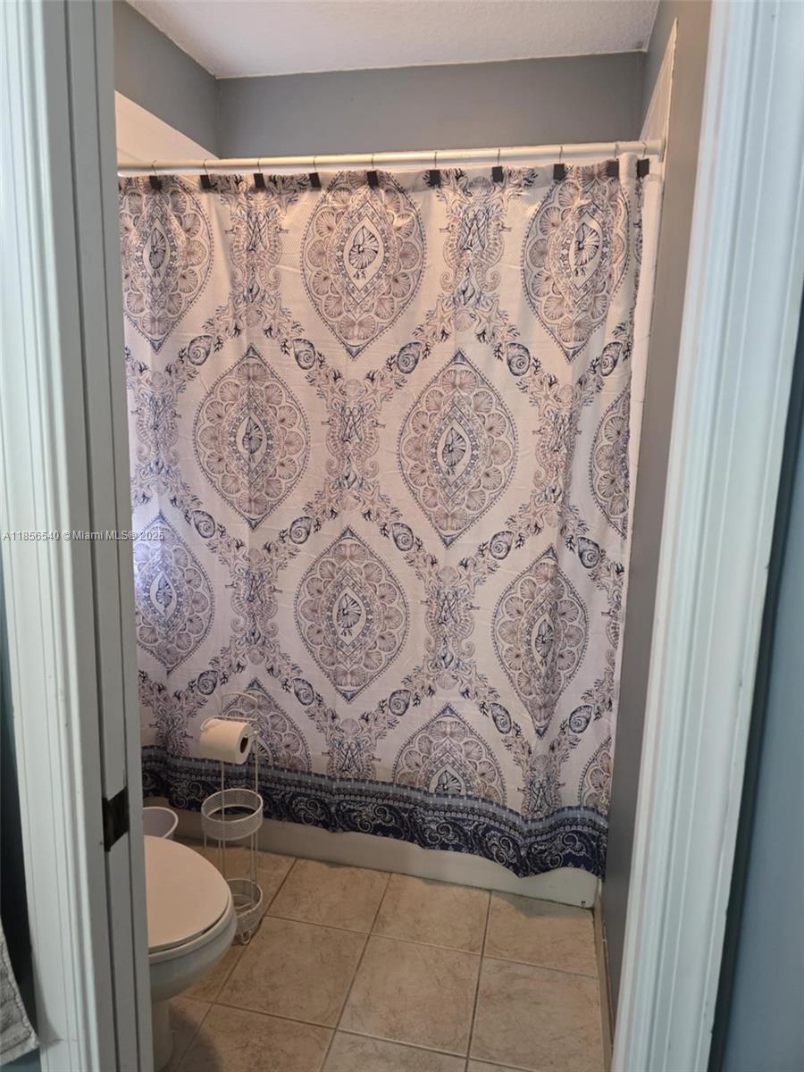 13994 Southwest 278th Street Homestead, FL 33032 - Photo 17 of 19 a bathroom with a toilet and shower curtain