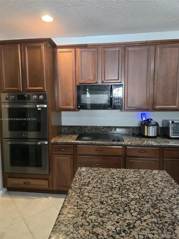 a kitchen with a granite countertop sink and cabinets