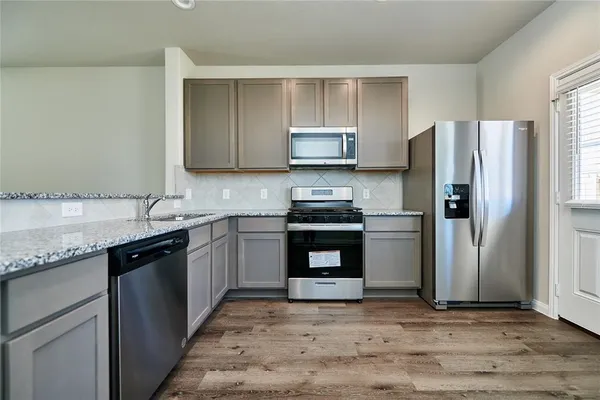 a kitchen with stainless steel appliances granite countertop a refrigerator stove a sink and dishwasher