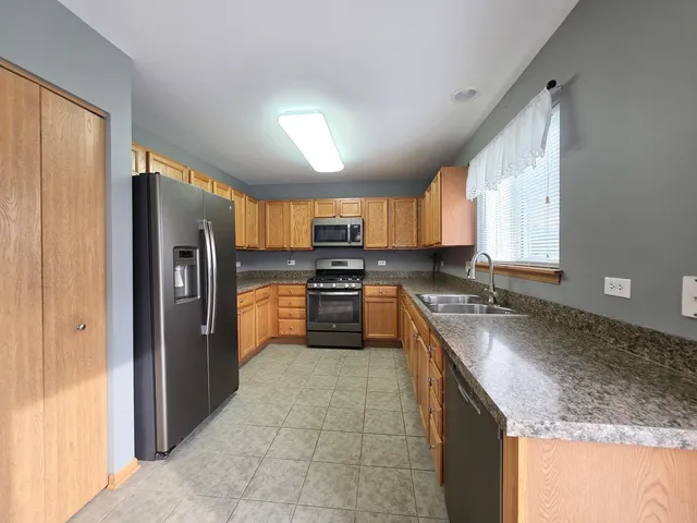 a large kitchen with granite countertop a stove refrigerator and a sink