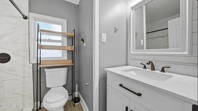 a bathroom with a toilet sink vanity and mirror