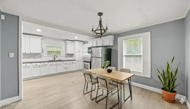 a kitchen with stainless steel appliances a dining table chairs a refrigerator and cabinets