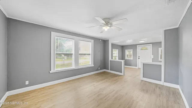 a view of an empty room with a window and wooden floor
