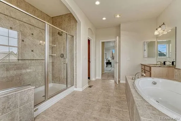 a large spacious bathroom with a tub shower and mirror